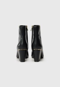 Black leather ankle boots with gold accent hardware, square heels, and a smooth finish. Side zipper detail enhances functionality.