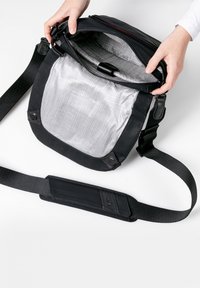 Borsa messenger nera con apertura con zip, fodera interna grigia a motivo a righe e tracolla regolabile. Tessuto morbido e hardware robusto.