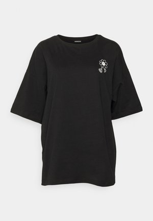 Camiseta de algodón negra con mangas cortas de gran tamaño. Presenta un diseño de flor bordado en blanco en el lado izquierdo del pecho. Textura suave.