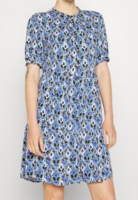 Vestido azul con estampado, de mangas cortas abullonadas, que presenta un diseño de diamantes y espirales multicolores sobre un fondo negro.
