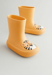 Bottes en caoutchouc jaunes avec un design de visage de tigre sur la tête ; semelle texturée et partie supérieure lisse ; hauteur courte avec bords arrondis.