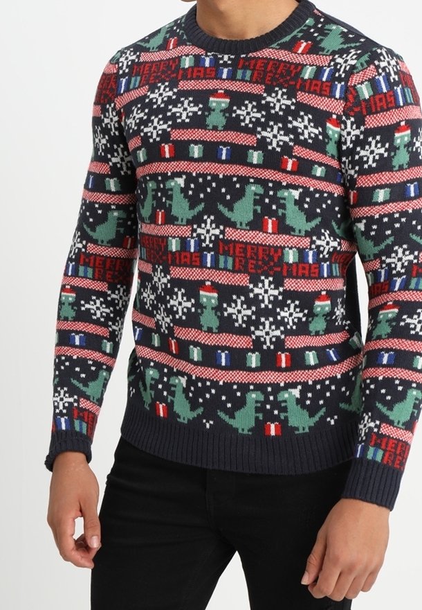 Pull de Noël bleu marine avec des dinosaures verts, des flocons de neige, des cadeaux et le texte rouge « Merry Rex-Mas » porté par une personne.