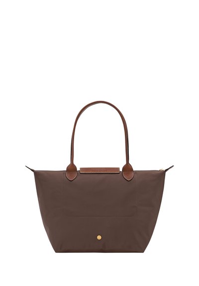 Brown tote bag with two leather handles, a front flap detail, and a small round gold button near the base, isolated on white background.