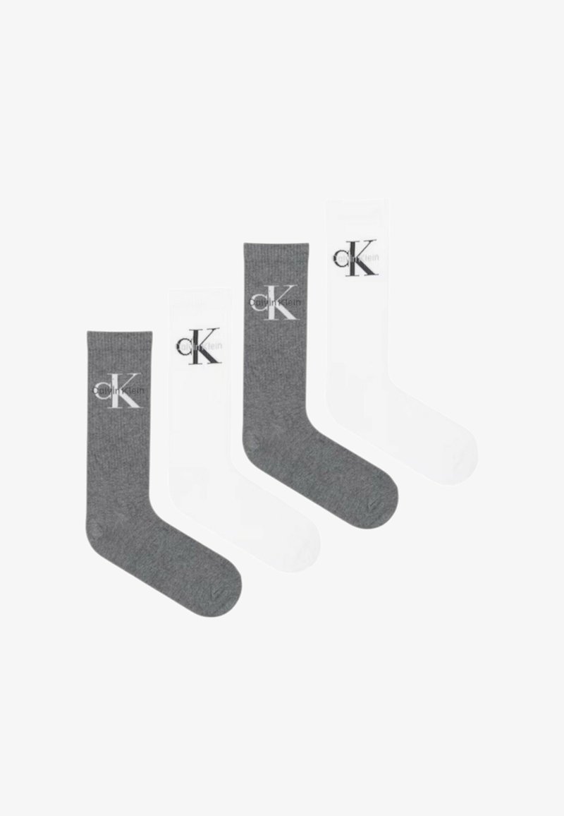 Dos pares de calcetines cortos, uno gris y otro blanco, cada uno con el logo "cK" de Calvin Klein impreso cerca de la parte superior.