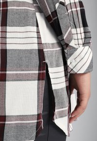 Bomuldsskjorte med tern i røde, grå og hvide farver, med knappet manchet og sideslidser for bevægelsesfrihed.