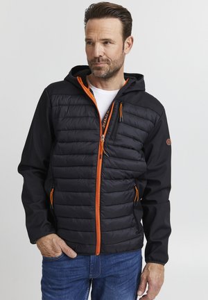 Veste noire avec zip et accents orange, présentant un devant matelassé, une capuche et des poches latérales. Texture douce, coupe athlétique.
