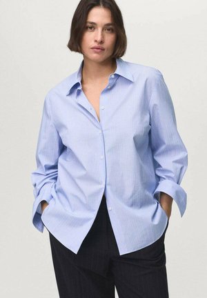 Camicia button-up azzurro chiaro con strisce verticali bianche, maniche lunghe arrotolate e colletto classico. Realizzata in tessuto di cotone.