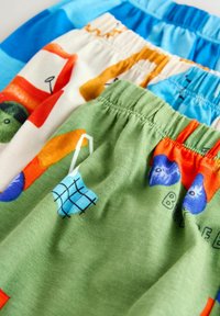 Három pár mintás rövidnadrág: kék, fehér piros és narancssárga grafikával, valamint zöld kék és narancssárga mintákkal. Puha anyag, rugalmas derékpánttal.