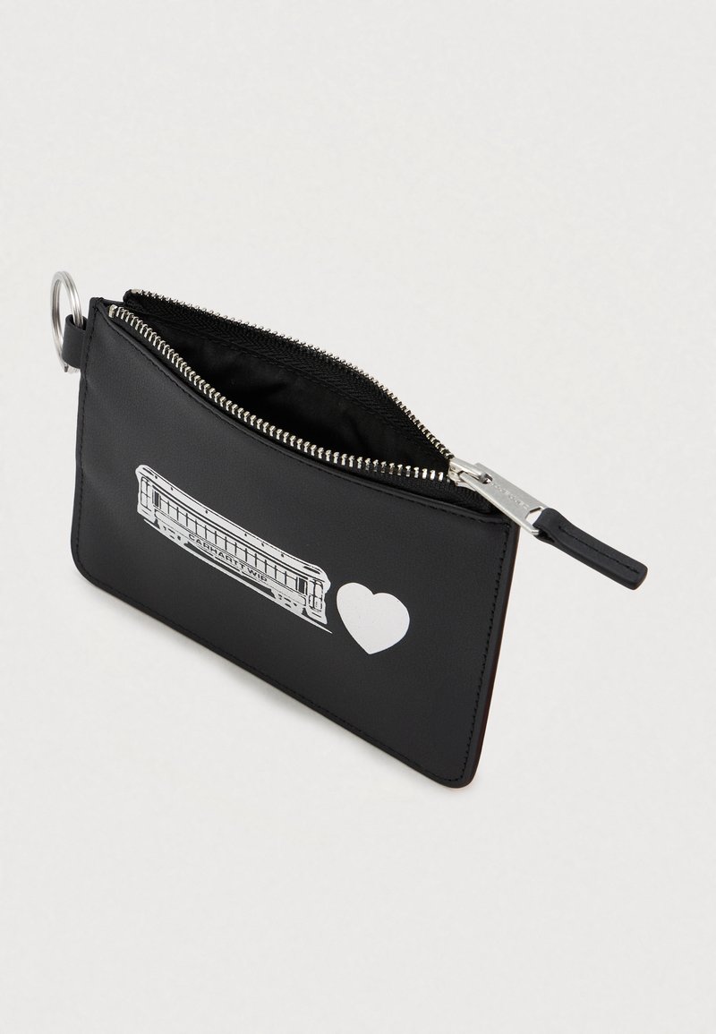 Sort lynlås pung med en hvid mundharmonika og et hjertegrafik på forsiden samt en metalnøglering fastgjort.