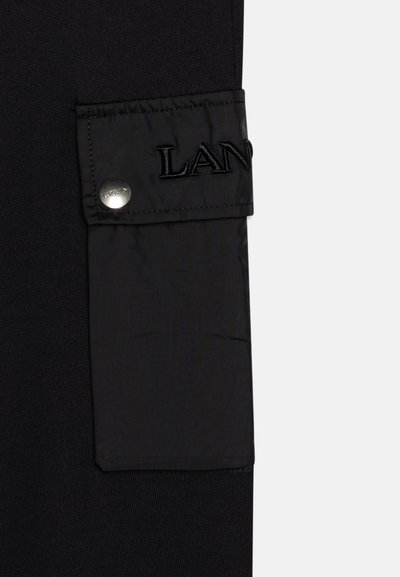Pantalon cargo noir avec un tissu texturé et une poche lisse. La poche est dotée d'une fermeture à pression et d'un logo brodé.