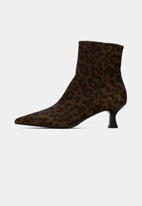 Botín de tobillo con estampado de leopardo, hecho de un tejido suave, con punta afilada y un tacón bajo y afilado. La paleta de colores incluye tonos oscuros de marrón y manchas negras.