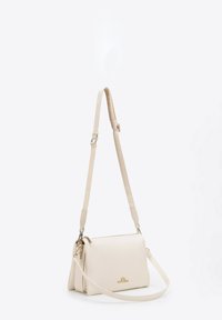 Krémová kožená taška s designem klopy, nastavitelným popruhem, zlatými kovovými detaily a minimalistickým brandingem na přední straně.