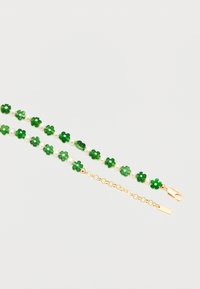 Βραχιόλι με εναλλασσόμενα χάντρες σε σχήμα τριφυλλιού πράσινου χρώματος και λευκές πέρλες, με κούμπωμα αλυσίδας από χρυσό σε λευκό φόντο.