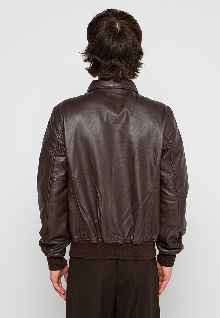 Veste en cuir marron de type bombardier avec des poignets et une ceinture côtelés, présentant un col classique et une texture lisse. La vue arrière montre des détails de couture.