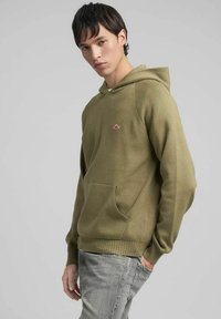Felpa con cappuccio verde oliva in tessuto strutturato, con tasca a marsupio e polsini a costine. Piccolo logo rosso sul petto, design a vestibilità comoda.