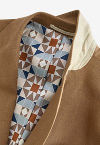 Braune Jacke mit glatter Textur und einem hellen Kragen. Das Futter zeigt ein geometrisches Muster in Blau, Braun und Creme.