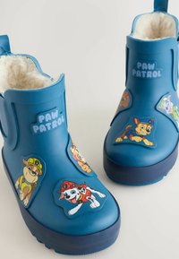 Stivali da pioggia in gomma blu con fodera morbida, dotati di adesivi colorati dei personaggi di Paw Patrol sui lati e una suola texturizzata per una buona presa.