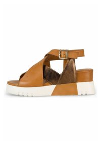Sandale en cuir tan avec un design à bandoulière croisée, accent métallique et semelle blanche. Elle dispose d'une boucle réglable et d'un bout ouvert. Détails texturés sur les côtés.
