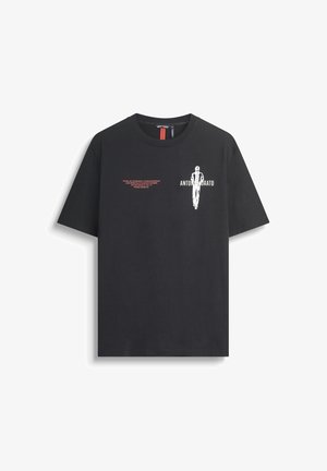 T-shirt de algodón negro con un gráfico blanco y texto rojo en la parte delantera. Cuello redondo estándar y mangas cortas.