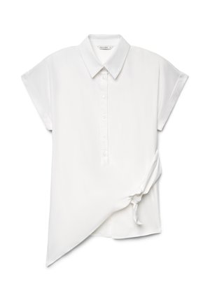Blusa bianca asimmetrica a maniche corte con colletto, bottoni frontali e dettaglio con nodo laterale su sfondo uniforme.