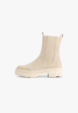 Beige suède enkellaars met chunky zool, elastische zijpanelen en trekstrips aan de hiel en voorkant.