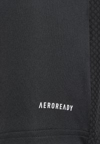 Tejido atlético negro con una textura suave. Presenta el logo blanco "AEROREADY". El panel lateral tiene un sutil patrón texturizado para mejorar la transpirabilidad.
