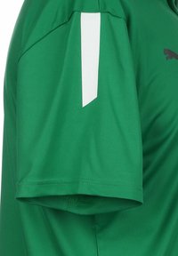 Maglietta sportiva verde con maniche corte, un accento bianco sulla spalla e una texture di tessuto liscia e traspirante.