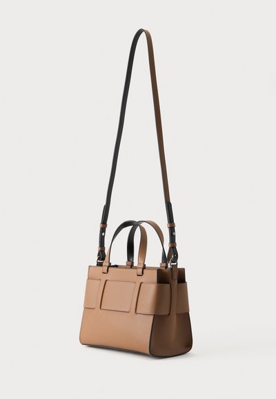 Bolso de mano de cuero marrón claro de tamaño mediano con correa de hombro ajustable en negro y marrón claro y dos pequeñas asas sobre fondo blanco.