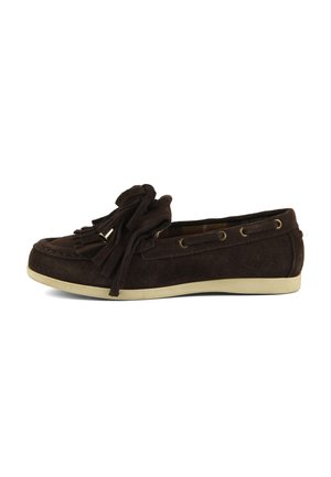 Mocassin en daim brun foncé avec pompons et œillets en métal, semelle beige et détails cousus sur le profil supérieur.