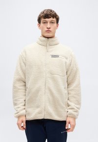 Μπεζ ζακέτα από φλις με ψηλό γιακά, φερμουάρ πλήρους μήκους και τσέπη στο στήθος. Μαλακή υφή και άνετη εφαρμογή. Διαθέτει λογότυπο στο μπροστινό μέρος.