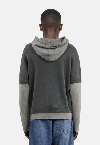 Felpa bicolore grigia con cappuccio e maniche grigie chiare. Orlo e polsini a coste. Presenta una vestibilità comoda e una trama morbida. Design informale.
