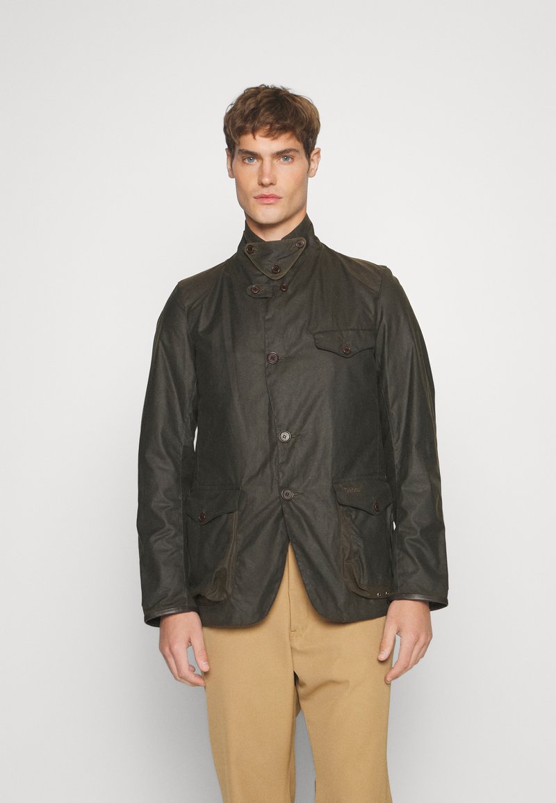Dark green waxed cotton jacket with a high collar, four front pockets, and button closures, featuring a slightly textured finish.