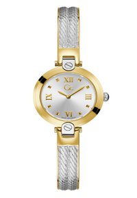 Orologio con finitura dorata e quadrante argentato. Numeri romani e indici a forma di diamante per le ore. Bracciale in metallo con un design intrecciato in argento.