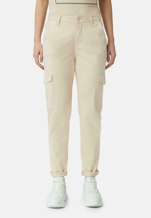 Beige cargobroek met zijzakken, taps toelopende pijpen en opgerolde boorden, gecombineerd met witte sneakers. Katoenen materiaal, gladde textuur.