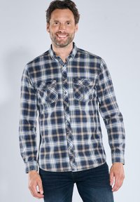 Kariertes Flanellhemd in Marineblau, Blau und Braun; mit Knopfverschluss vorne, zwei Brusttaschen, langen Ärmeln und abgerundetem Saum.