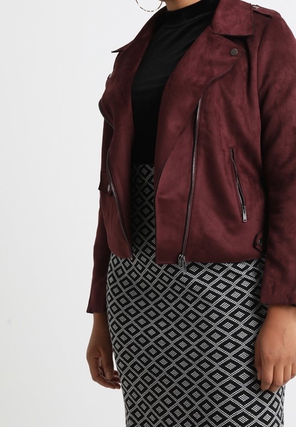 Giacca da motociclista in finta pelle scamosciata color bordeaux con cerniere e colletto a revers, abbinata a una gonna a matita con motivo a diamante bianco e nero.