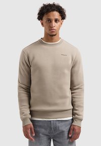 Beige sweatshirt met een geribde ronde hals, lange mouwen en subtiele branding op de borst. Gemaakt van een zachte, gestructureerde stof.