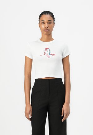 White cropped t-shirt with short sleeves featuring a colorful mermaid graphic. Paired with high-waisted black trousers.