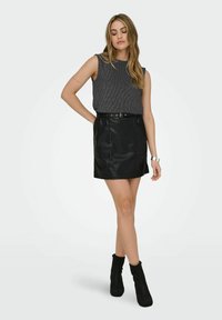 Szary prążkowany top bez rękawów w połączeniu z czarną mini spódnicą z sztucznej skóry, z elastycznym pasem i paskiem z elementami ozdobnymi w kolorze srebrnym.