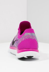 Růžová sportovní obuv s texturovaným pleteným svrškem, černým logem a bílou podrážkou. Vyznačuje se jedinečným vícebarevným vzorem po celém povrchu.