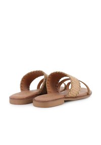 Sandalias abiertas de dedo hechas de un textil trenzado marrón con una suela de cuero plana y suave. Incluyen correas laterales y costuras detalladas a lo largo de los bordes.