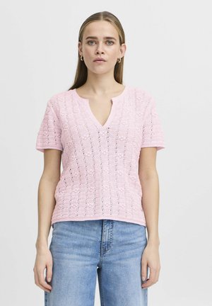 Lyserød strikket kortærmet top med V-hals, struktureret mønster og rund kant. Sammenstylet med lyseblå denimjeans.