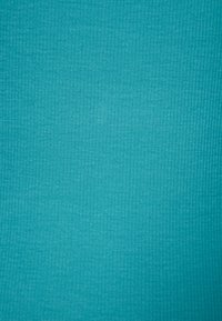 Turkusowa dzianina prążkowana o gładkiej fakturze, równym wzorze i lekko rozciągliwym wyglądzie, idealna do zastosowań odzieżowych lub tapicerskich.