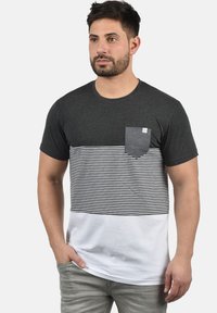 Camiseta de manga corta con una sección superior de color gris oscuro, rayas horizontales en blanco y negro en la sección media, y una sección inferior completamente blanca.