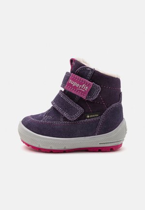 Paarse suède enkelboot met roze accenten, twee klittenbandsluitingen, witte voering en een gestructureerde grijze buitenzool. Voorzien van Gore-Tex branding.