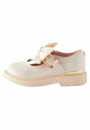 Chaussure Mary Jane en cuir verni beige clair, avec un grand nœud, une fermeture à boucle et un talon orné d'accent doré. Semelle texturée.