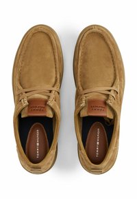 Hellbraune Wildlederschuhe mit Mokassin-Design, ausgestattet mit einer strukturierten Oberfläche, braunen Lederelementen und einer Gummisohle.