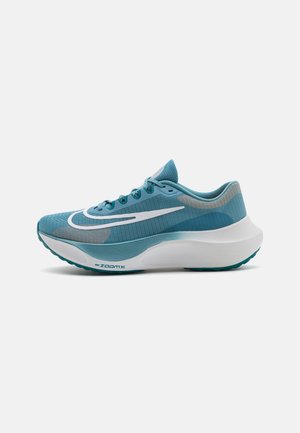 Türkisblauer Laufschuh mit weißer Sohle, großem weißem Swoosh-Logo, atmungsaktivem Mesh-Obermaterial und gepolsterter, gebogener Fersensohle.