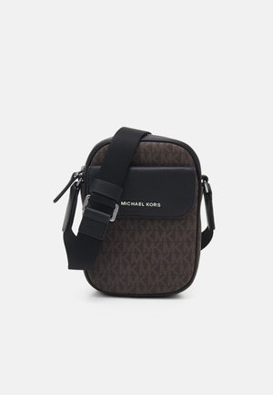 Compact brown crossbody bag with repeating "MK" pattern, black front pocket, adjustable black strap, and silver "MICHAEL KORS" logo.