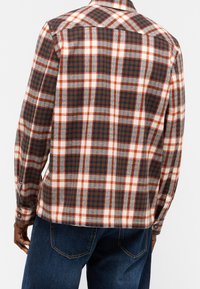 Košile s dlouhým rukávem v kostkovaném vzoru v hnědé, modré a bílé barvě, vyrobená z měkké látky s manžetami na knoflíky a špičatým límcem.